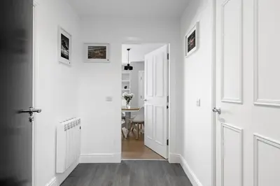 a hallway with white walls and white doors and a table at Castle Street Apartments - Luxury Kerrycroy Ground Floor Apartment in Rothesay