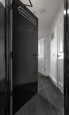 a black door with a sign on it in a hallway at Castle Street Apartments - Luxury Kerrycroy Ground Floor Apartment in Rothesay