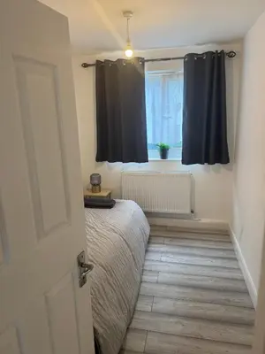 a bedroom with black curtains and a bed and a window at Modern 3-Bed Flat Stylish Family-Friendly in Moffat