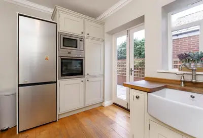 a kitchen with white cabinets and a stainless steel refrigerator at 2 On The Green in Moffat