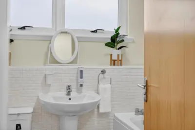 a white bathroom with a sink and a mirror at Modern 2-Bedroom flat in Glasgow city centre, near Galsgow Green in Glasgow