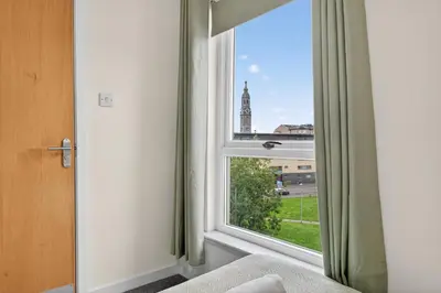 a room with a window with a view of a clock tower at Modern 2-Bedroom flat in Glasgow city centre, near Galsgow Green in Glasgow