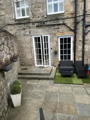 a stone building with a patio with chairs in front of it at Walker Apartment in Edinburgh