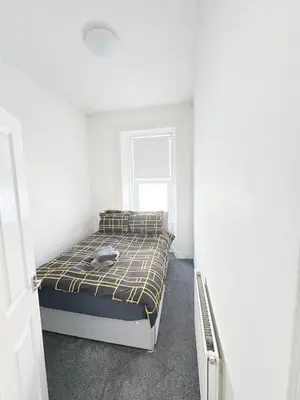 a bedroom with a bed in a white room at 2Bed Gla Green, Walk Dist City Centre in Glasgow