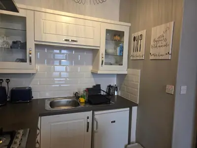 a small kitchen with white cabinets and a sink at Stylish Flat in Historic Edinburgh city centre home in Edinburgh