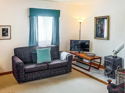 a living room with a couch and a television at Tigh An Droma Lodge in Whiting Bay