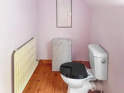 a bathroom with a white toilet with a black seat at Tigh An Droma Lodge in Whiting Bay