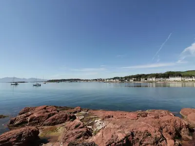 a large body of water with rocks in the foreground at Cosy In in Millport