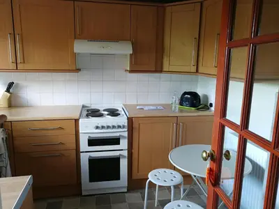 a kitchen with wooden cabinets and a stove and a table at Three Bedroom Apartment Glasgow in Glasgow