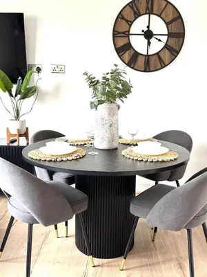 a black dining room table with chairs and a clock at Newtown Hideaway in Boʼness
