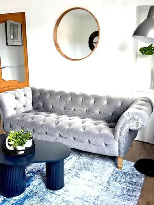 a living room with a leather couch and a round mirror at Newtown Hideaway in Boʼness
