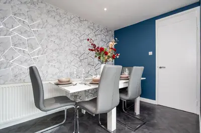 a dining room with a table with chairs and a vase of flowers at 2 Bedroom House-Free Parking in Rosyth