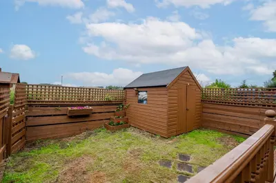 a small wooden shed sitting in a fence at 2 Bedroom House-Free Parking in Rosyth