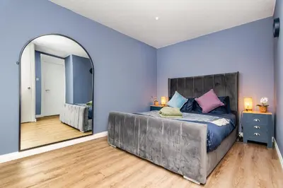 a bedroom with a large bed and a mirror at 2 Bedroom House-Free Parking in Rosyth