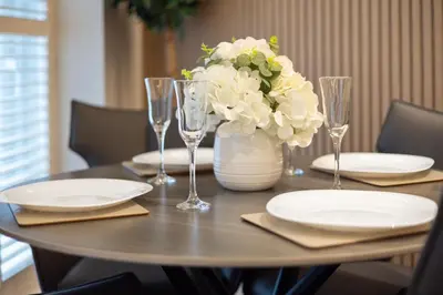 a table with plates and glasses and a vase with flowers at City Centre Luxury Studio for 2 in Edinburgh