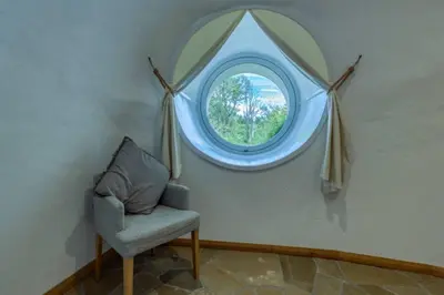 a chair in a room with a round window at The Warren - Hobbit House and Hot Tub at Loch Tay in Lawers