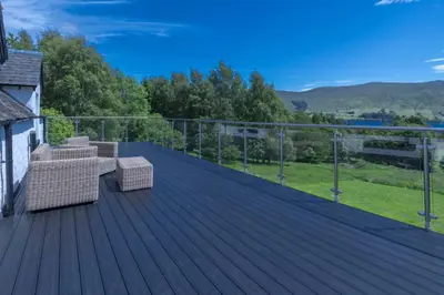 a deck with two couches and chairs on it at Loch Tay, Estate House with Panoramic Vistas in Lawers