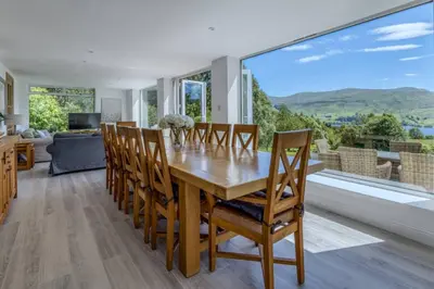 a dining room with a table and chairs and a large window at Loch Tay, Estate House with Panoramic Vistas in Lawers