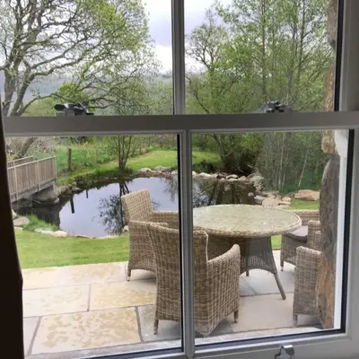 a view from a window of a patio with a table and chairs at Wishing Well Cottage at Loch Tay and Hot Tub in Lawers