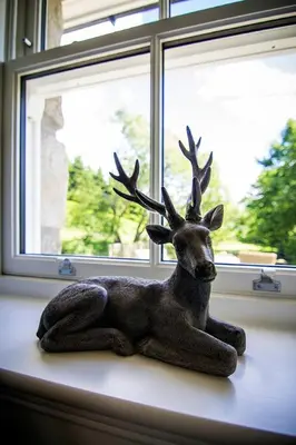 a statue of a deer sitting on a window sill at Wishing Well Cottage at Loch Tay and Hot Tub in Lawers