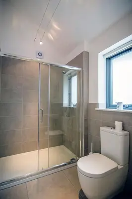 a bathroom with a toilet and a glass shower at Wishing Well Cottage at Loch Tay and Hot Tub in Lawers