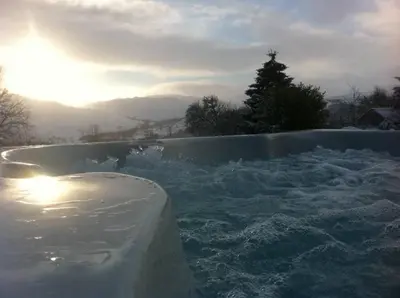 a hot tub covered in snow with a tree in the background at Sams Cottage with Loch Tay Vistas and Hot Tub in Lawers