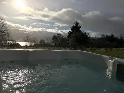a bath tub filled with water on top of a field at Sams Cottage with Loch Tay Vistas and Hot Tub in Lawers