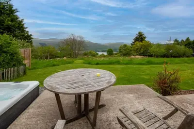 a wooden table with a ball on it next to a tub at Sams Cottage with Loch Tay Vistas and Hot Tub in Lawers