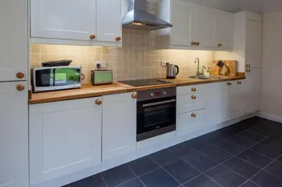 a kitchen with white cabinets and a microwave at Loch Tay Bothy Cottage with Hot Tub in Lawers