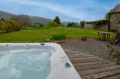 a hot tub on a wooden deck in a yard at Loch Tay Bothy Cottage with Hot Tub in Lawers