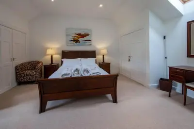a large bedroom with a bed and a chair at Loch Tay Bothy Cottage with Hot Tub in Lawers
