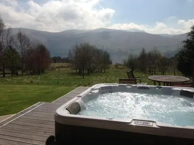 a hot tub on a deck with a view of mountains at Ben Lawers Rest Cabin - Hot Tub and Loch Tay Vistas in Lawers