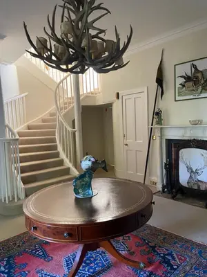 a living room with a table and a chandelier at Fordie Lodge in Comrie
