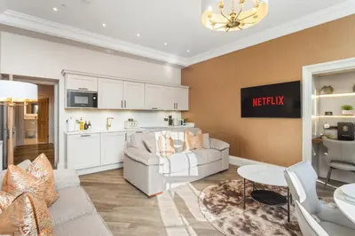 a living room with a couch and a kitchen at Prime Central Edinburgh 2 bed in Edinburgh