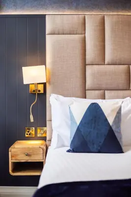 a bed with a blue and white pillow and a lamp at Prime Central Edinburgh 2 bed in Edinburgh