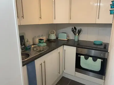 a kitchen with white cabinets and a sink and a stove at Quirky Cottage Central Bathgate in Bathgate