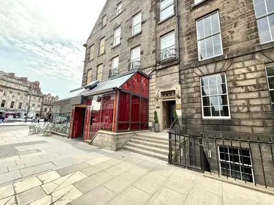 a brick building with a red door next to a building at Prime Central Edinburgh 2 bed in Edinburgh