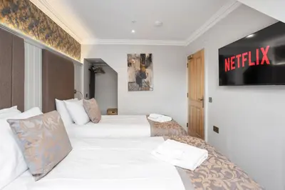 two beds in a hotel room with a netflix sign on the wall at Central Edinburgh Prime Luxury 3 bed in Edinburgh