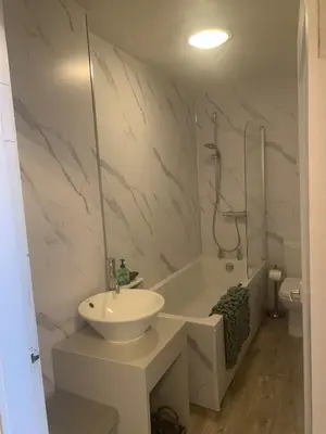 a white bathroom with a sink and a bath tub at Highland Hideaway Helensburgh in Helensburgh