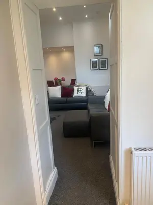 a hallway with a living room with a couch and a chair at Highland Hideaway Helensburgh in Helensburgh