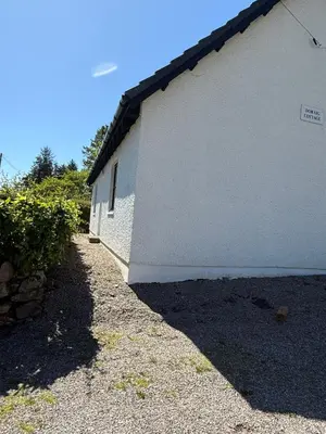 a white building with a sidewalk next to it at Highland Nook in Fort William