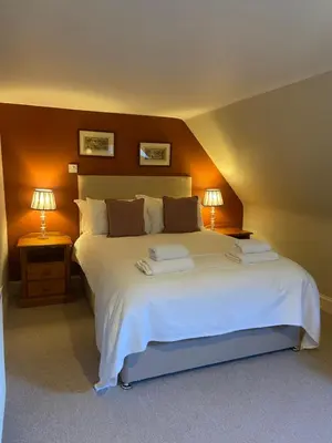 a bedroom with a large white bed with two lamps at Fordie South Cottage in Comrie