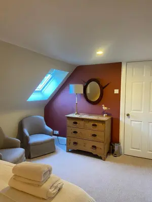 a bedroom with a bed and a dresser and a mirror at Fordie South Cottage in Comrie