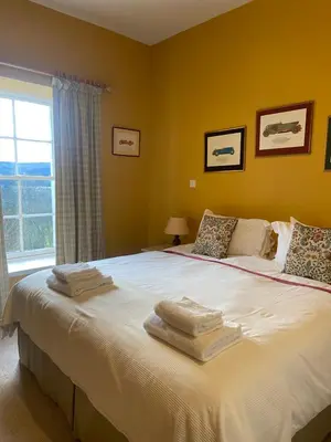 a bedroom with a large bed with towels on it at Fordie South Cottage in Comrie