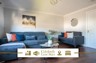 a living room with a blue couch and a chair at Mercer Apartment in Alloa