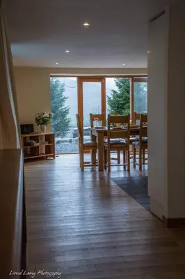a dining room with a table and chairs and windows at The Barn on Loch Tay - Hot Tub in Lawers