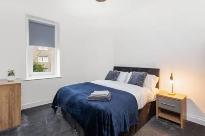 a white bedroom with a bed and a window at Stylish Stay in Inverkeithing. in Fife