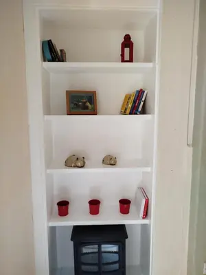 a book shelf with three red cups next to a fireplace at Lovely flat in Gorgie, Edinburgh in Edinburgh