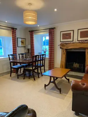 a living room with a table and chairs and a fireplace at Fordie West Cottage in Comrie