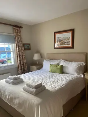 a bedroom with a white bed with towels on it at Fordie East Cottage in Comrie